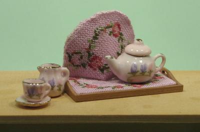 A miniature teapot, jug and cup and saucer, with teacosy and tea tray
