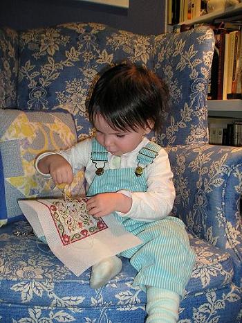 Two and a half year old little girl stitching a dollhouse needlepoint carpet